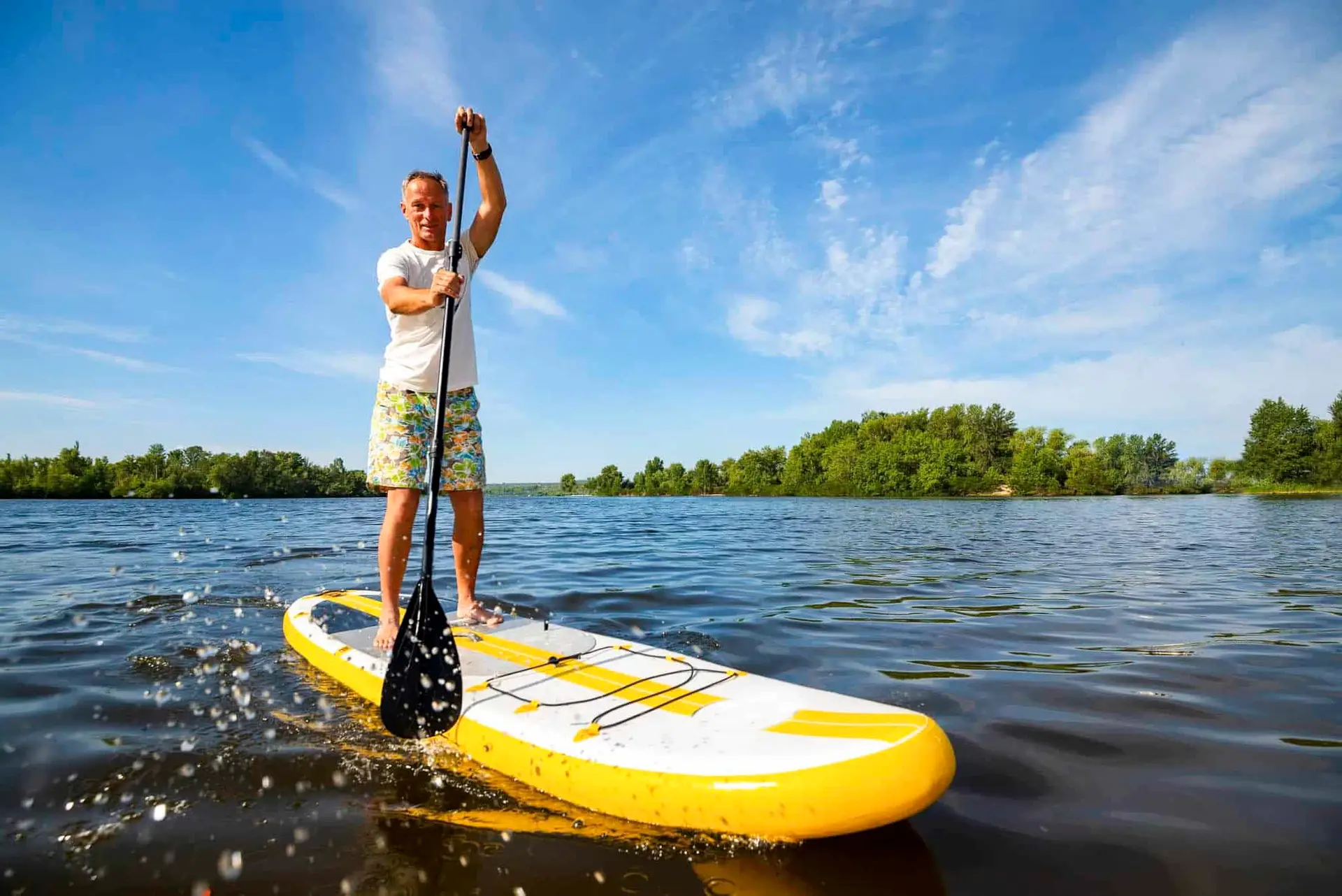 Mann steht mit Paddel auf einem Stand Up Paddel (SUP) und fährt auf dem Wasser, SUP Verleih Schwerin