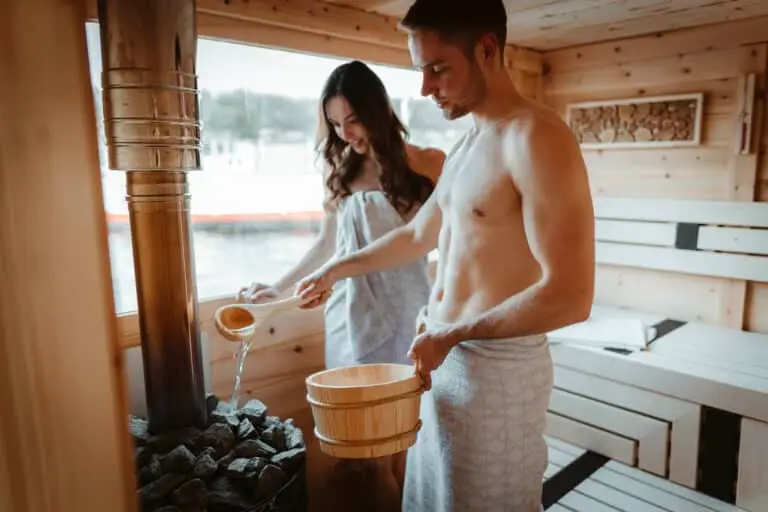 VINDUA Hausboote Schwerin, Pärchen kippt Wasser über heiße Steine in einer Sauna, Saunahausboot Schwerin, Michelle Prehsmann, Lucas Hube